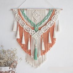 an orange and white wall hanging with tassels, beads and other things on it