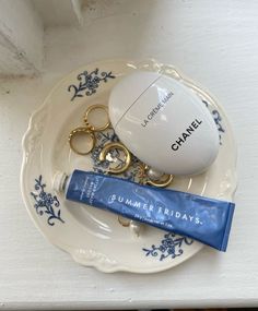 a white plate topped with gold scissors and a blue plastic bag next to a charm