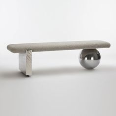 a concrete bench with a metal ball on it