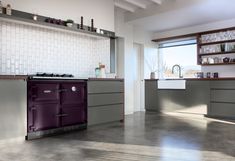 a purple stove top oven sitting inside of a kitchen next to a sink and window