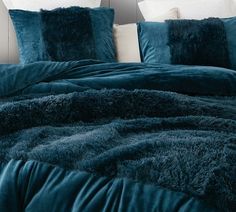 a bed with blue comforters and pillows on it