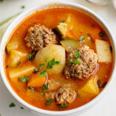 a white bowl filled with meatball soup on top of a table