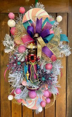 a christmas wreath hanging on the side of a wooden door with ornaments around it and a nutcracker figure