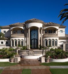 a large white house with palm trees in the front yard