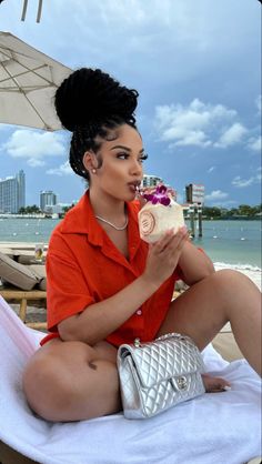 a woman in an orange shirt sitting on a beach chair eating a piece of cake