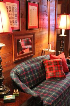 a living room with couches, lamps and pictures on the wooden wall behind them