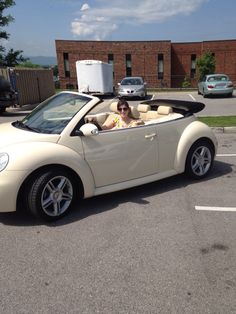 a woman sitting in the driver's seat of a convertible car with an open top