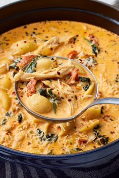 a ladle full of pasta and spinach in a blue pot with a spoon