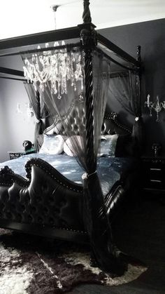 a black and white photo of a four poster bed with crystal chandelier hanging from the ceiling