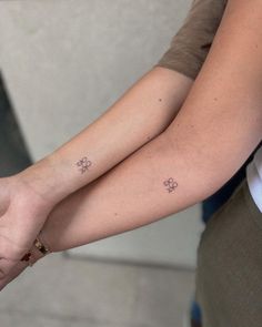 two people holding hands with small tattoos on them