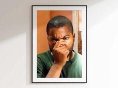 a man is looking at the camera with his hand on his nose while standing in front of a white wall