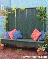 a wooden bench sitting in front of a blue building with potted plants on it