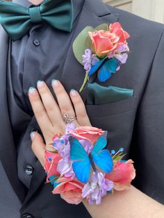 a man in a tuxedo with flowers and butterflies on his lapel