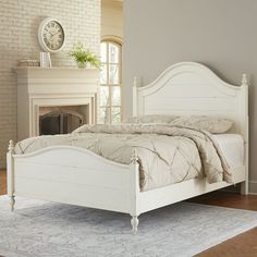 a white bed sitting in a bedroom next to a fireplace