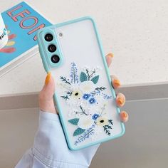 a woman holding up her phone case with flowers on it