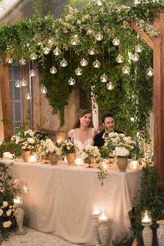 a couple sitting at a table surrounded by candles and greenery with the caption instagram