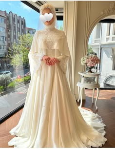 a woman in a wedding dress standing next to a window with a heart drawn on it