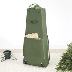 a green shopping bag sitting on top of a white floor next to a potted plant