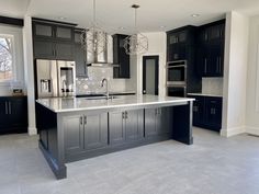 a large kitchen with black cabinets and stainless steel appliances