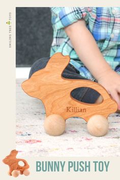 a child playing with a wooden toy that says bunny push toy on the front and side