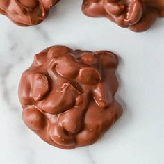 three cookies with chocolate frosting in the shape of elephants on a marble counter top