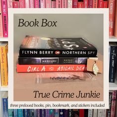 three books are stacked on top of each other in front of a bookcase full of books