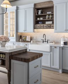 a large kitchen with white cabinets and wooden counter tops, along with a center island