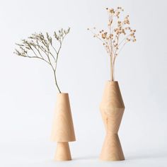 two wooden vases with flowers in them on a white surface, one is shaped like a cone