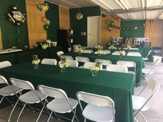 tables and chairs are set up in a room with green tablecloths on them