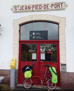 a bicycle parked in front of a red door that says jean - pied - de - port