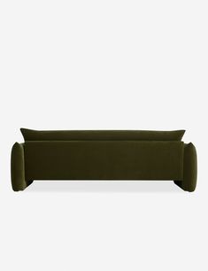 an olive green velvet sofa with two pillows on the back and one pillow in the middle