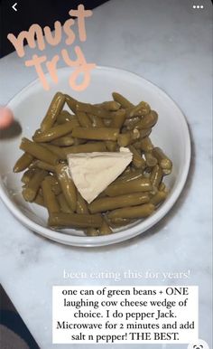 a bowl filled with green beans next to a piece of cheese on top of it