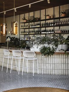 an empty bar with white chairs and plants