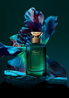 a bottle of perfume sitting on top of a wooden table next to purple and green flowers