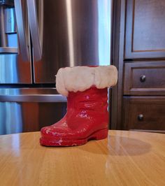 a pair of red boots sitting on top of a wooden table next to a refrigerator