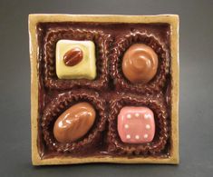 four chocolate candies in a box with nuts and cream toppings on the side