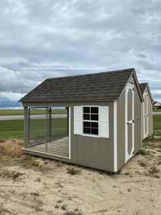 a small dog house in the middle of an open field with a fence around it