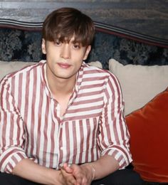 a man sitting on top of a couch next to a red and white striped shirt