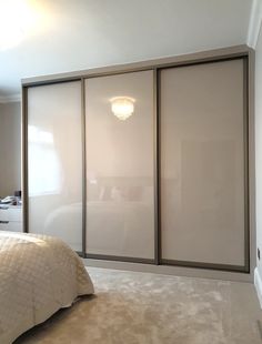 a bedroom with white walls and beige carpeted flooring, two sliding doors open to reveal a large bed