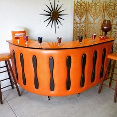 an orange bar with three stools next to it and a clock on the wall