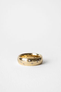 a gold wedding band with diamonds on the inside and outside, set against a plain white background