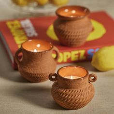 two brown vases sitting on top of a table next to a book