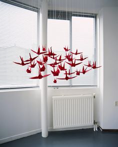 red origami birds hanging from the ceiling in front of a white radiator