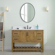 a bathroom vanity with two sinks and a round mirror above it, against a white wall