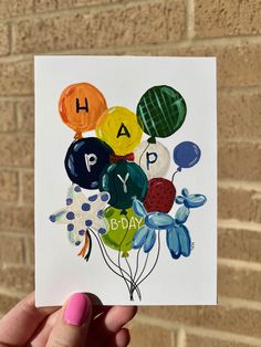 a hand holding up a birthday card with balloons