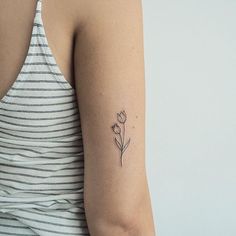 a woman's arm with a single flower tattoo on the left side of her arm