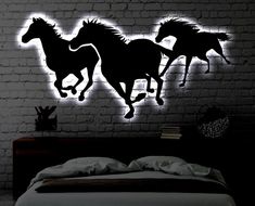 three horses running through the air on a brick wall in a bedroom with white bedding