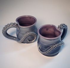 two coffee mugs sitting next to each other on top of a white countertop