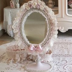 a white table topped with a mirror next to a vase filled with flowers and pearls