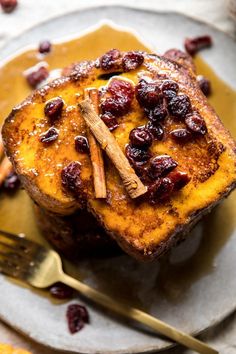 two pieces of french toast with cranberries and cinnamon on top, sitting on a plate